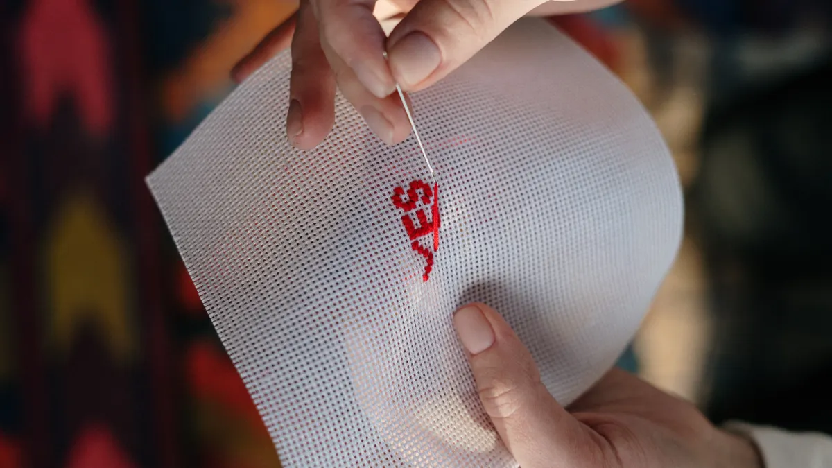 Hand stitching on white aida cloth in an embroidery hoop