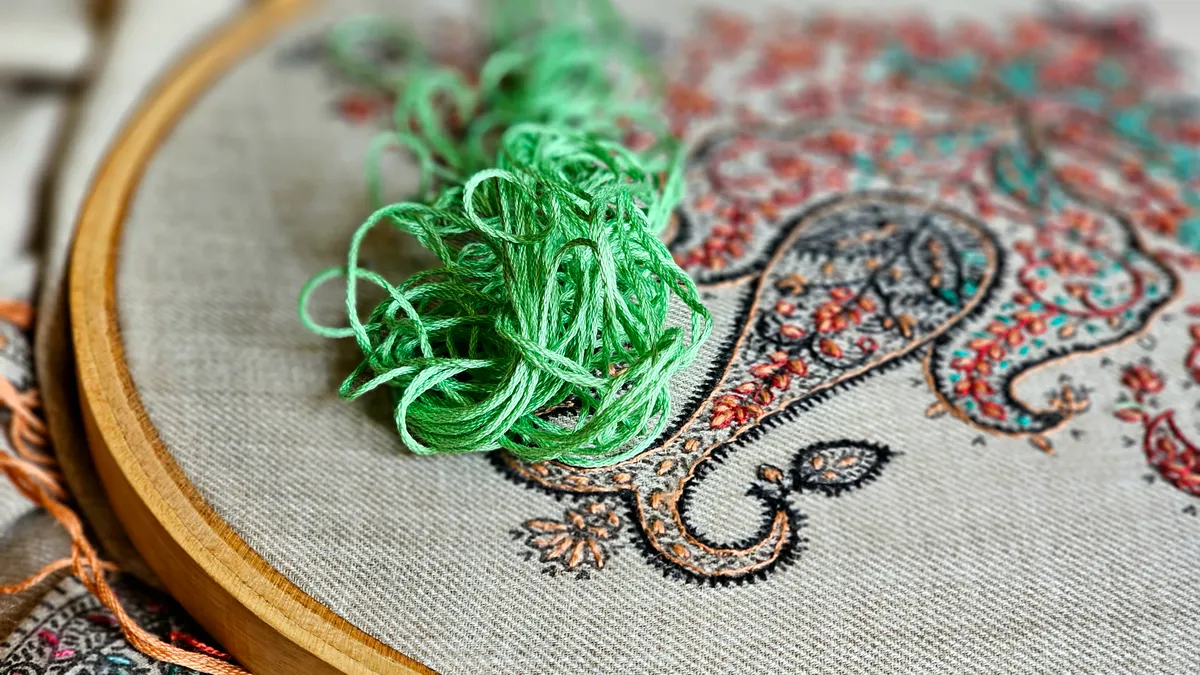 Embroidery hoop with loose thread and stitched fabric design