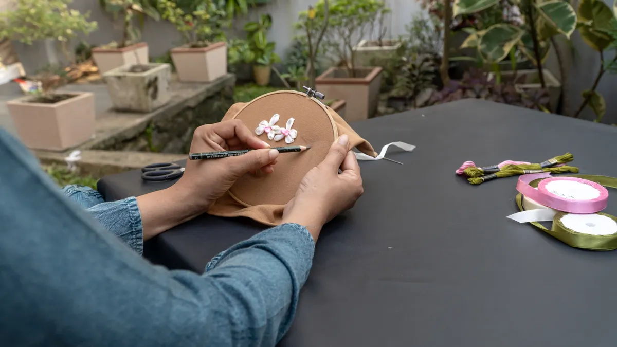 hands embroidering flowers in a hoop