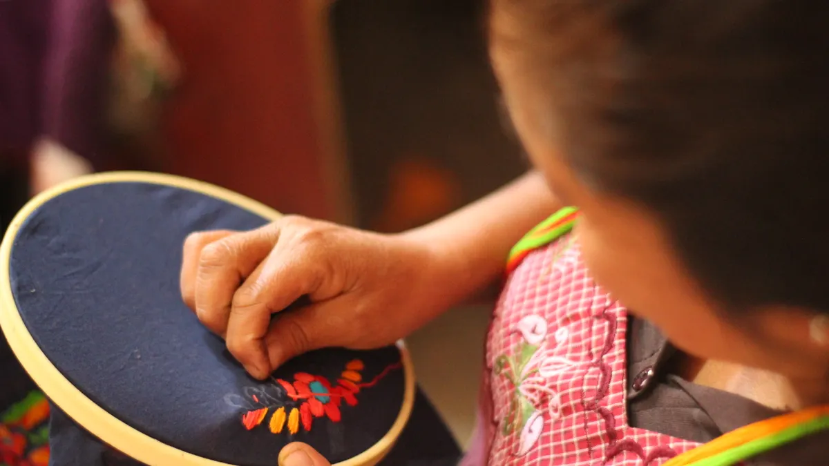 person embroidering colorful leaves in a hoop